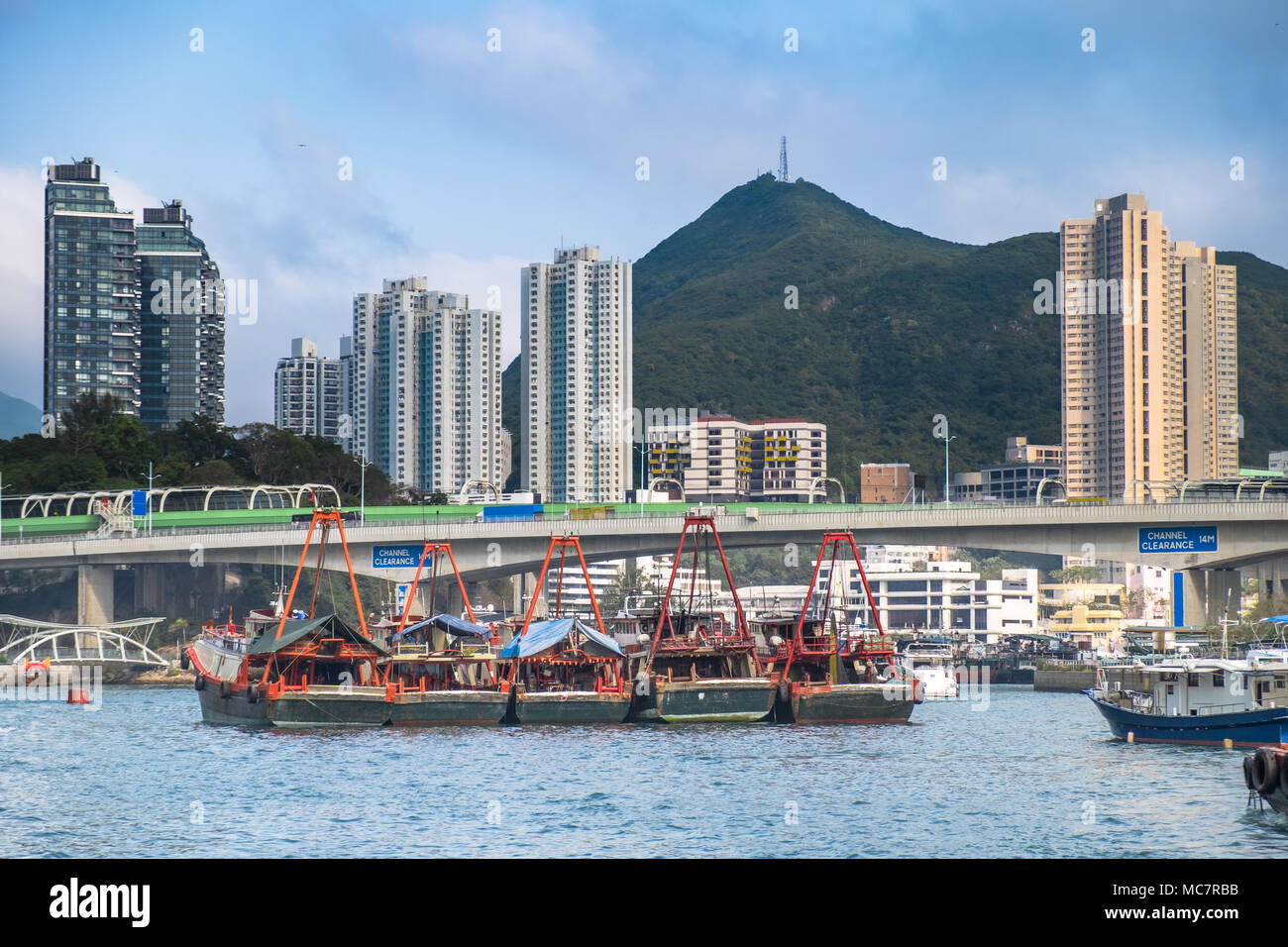 Fishing trawlers in Hong Kong Aberdeen Bay. Transport bridge, buildings, skyscrapers on background. City geometry and South East Asia beautiful nature Stock Photo