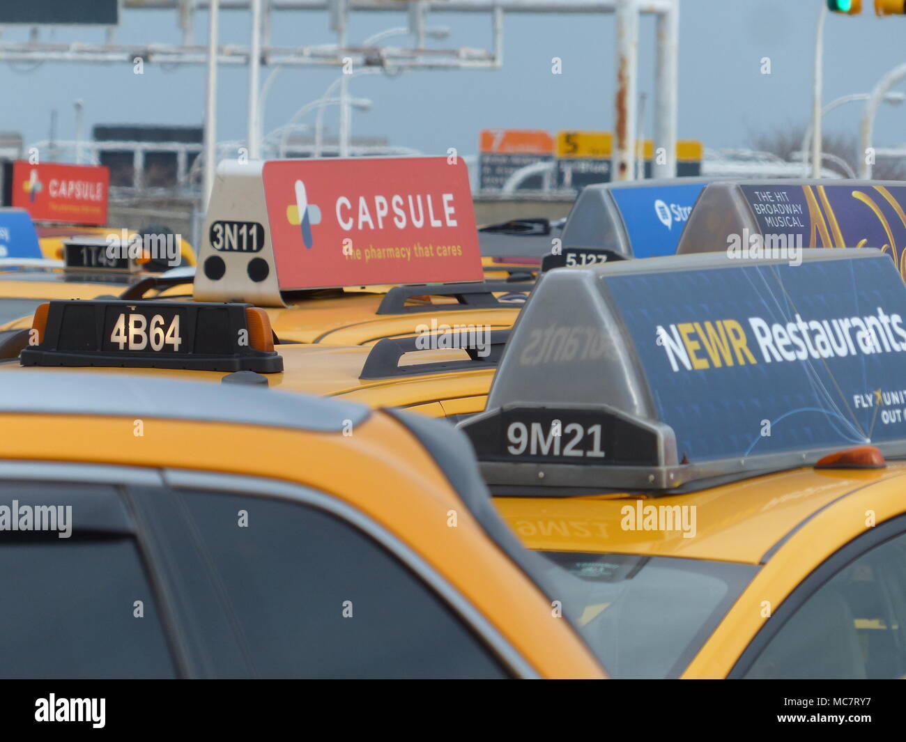 NYC taxis with rooftop advertisement waiting at JFK Central Holding Lot
