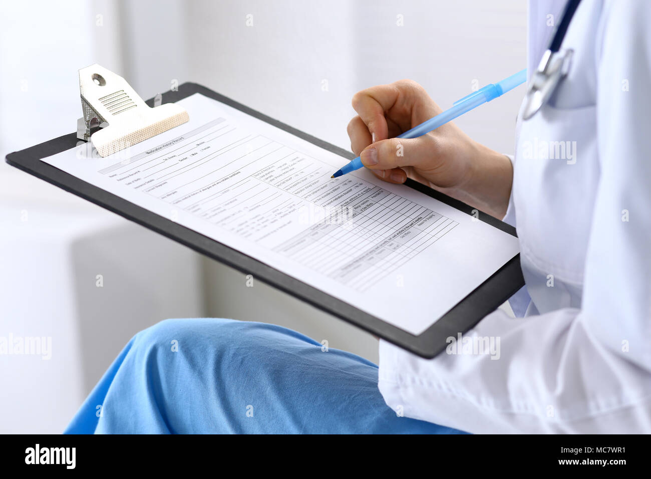 Female doctor filling up medical form on clipboard closeup. Physician ...