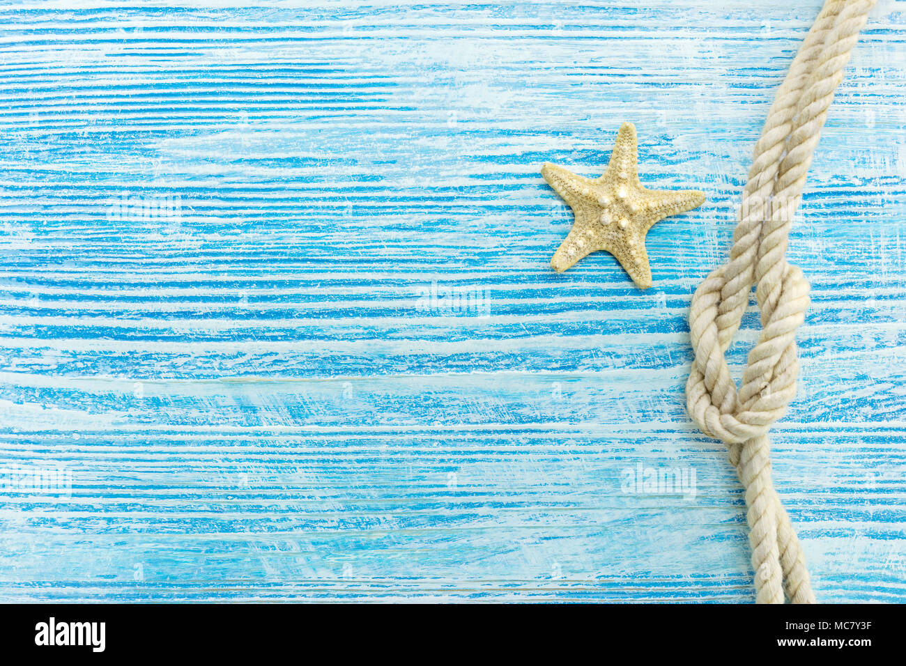 starfish and marine knot on weathered blue wooden surface. summer holiday background Stock Photo