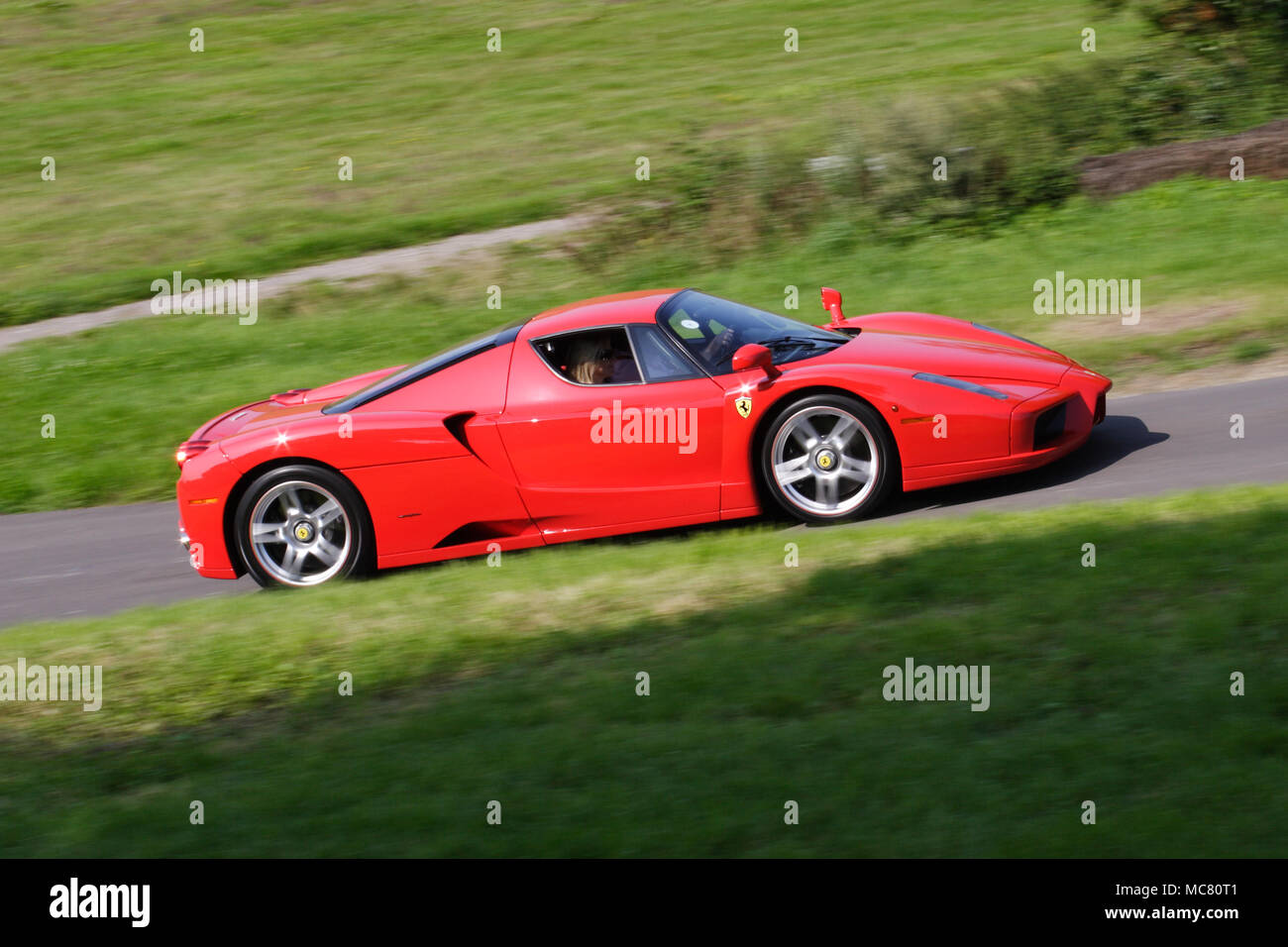 Profile (side view) of a sexy Red Ferrari Enzo mid-engined V12 hyper car driving fast Stock Photo
