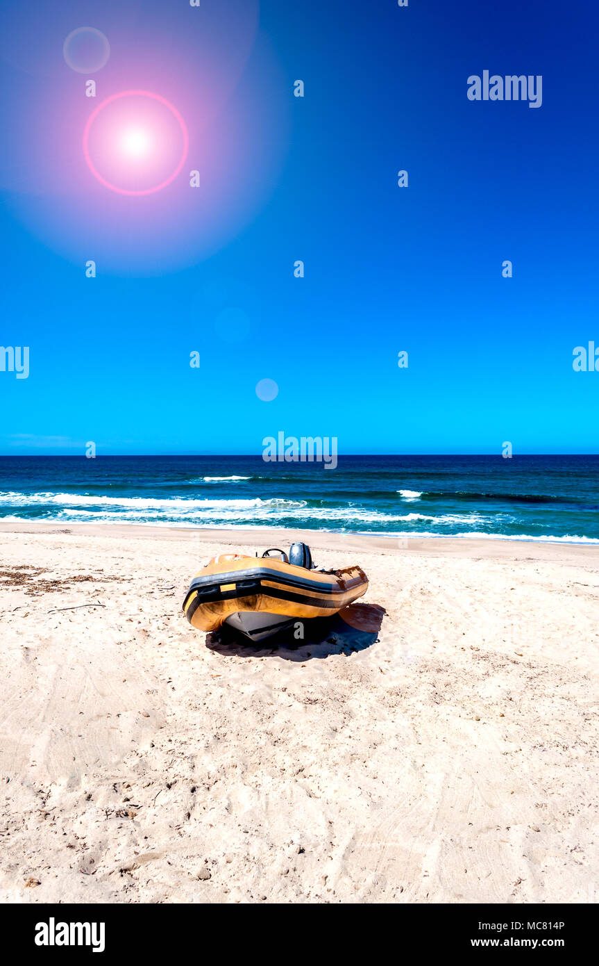 orange dinghy boat on the desert beach in sunny day with lens flare Stock Photo
