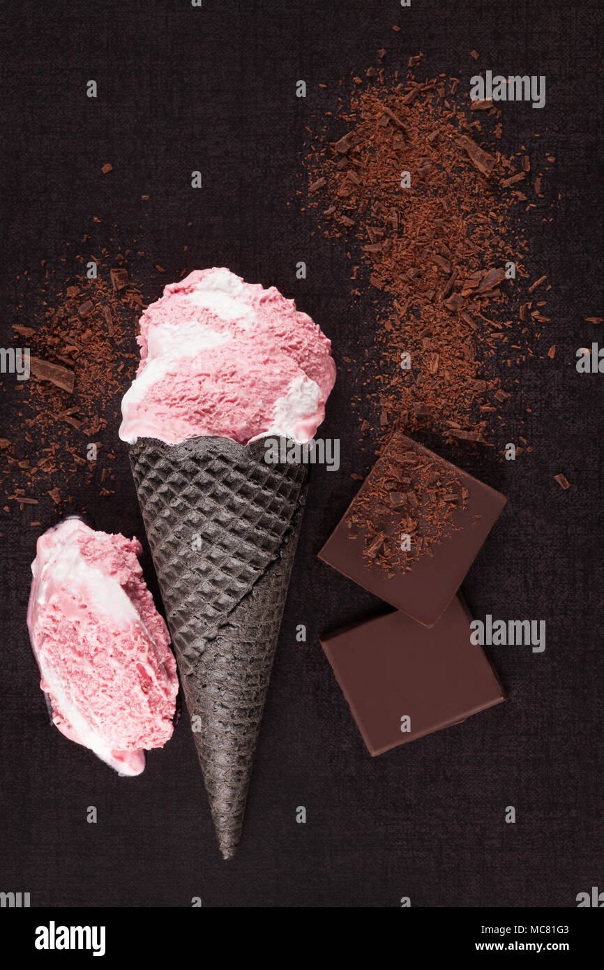 Delicious strawberry and chocolate ice cream on dark surface from above