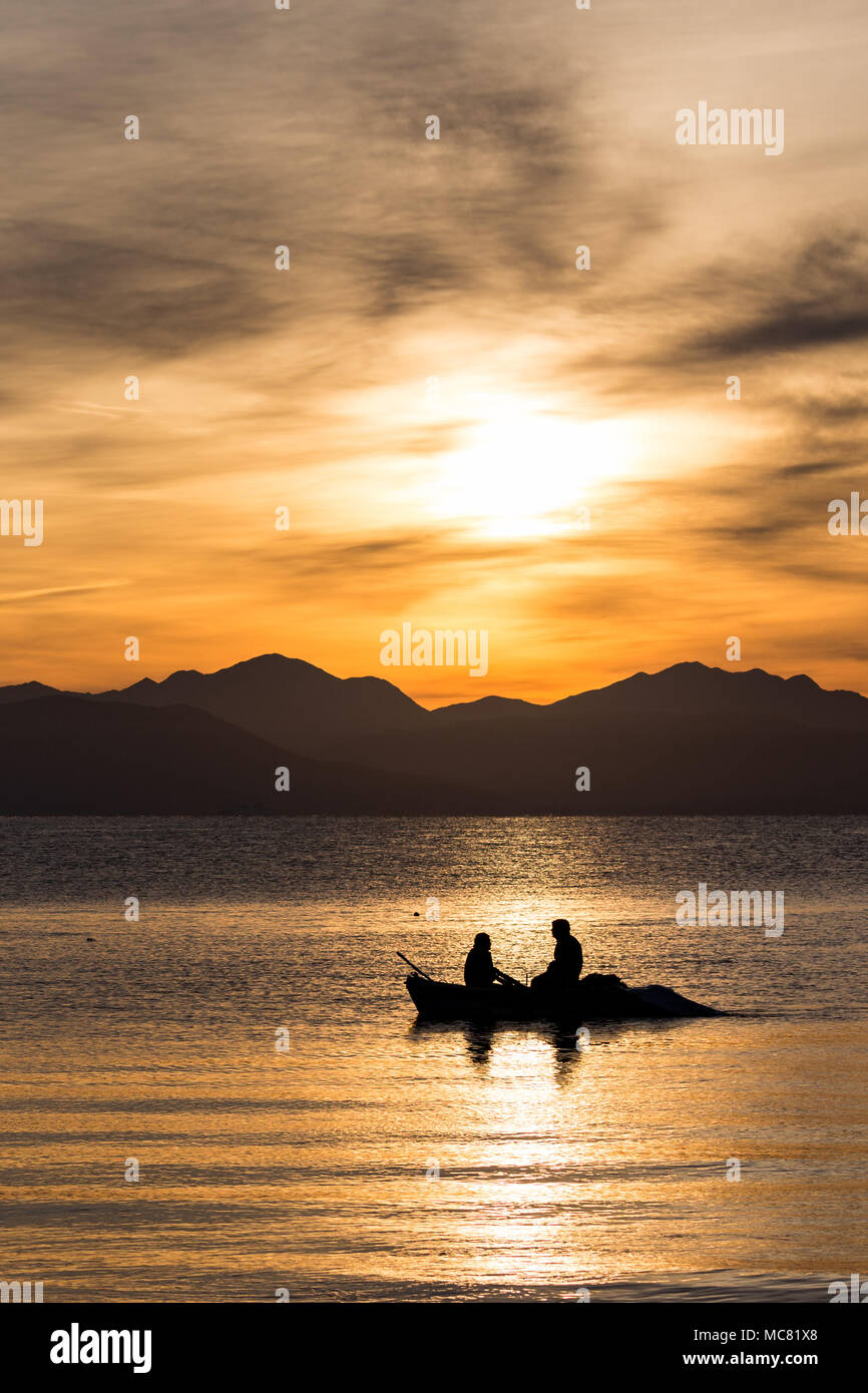 two men fishing from boat at sunset Stock Photo - Alamy
