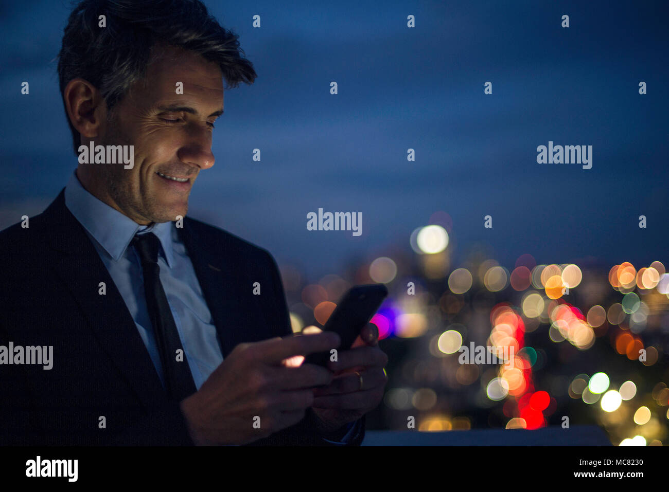 Businessman on high rise rooftop using mobile phone Stock Photo