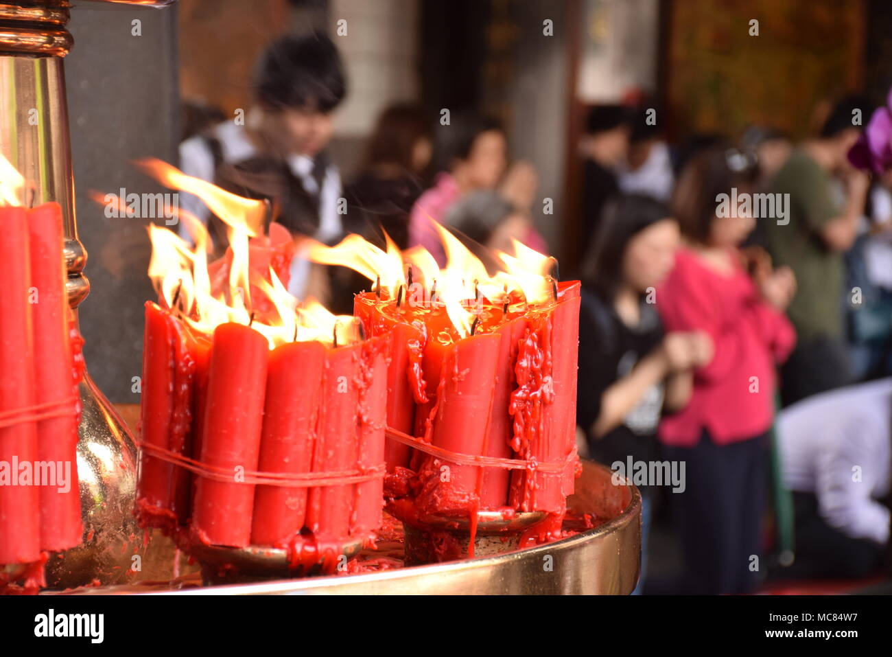 Red candles with blurred people praying in the background inside