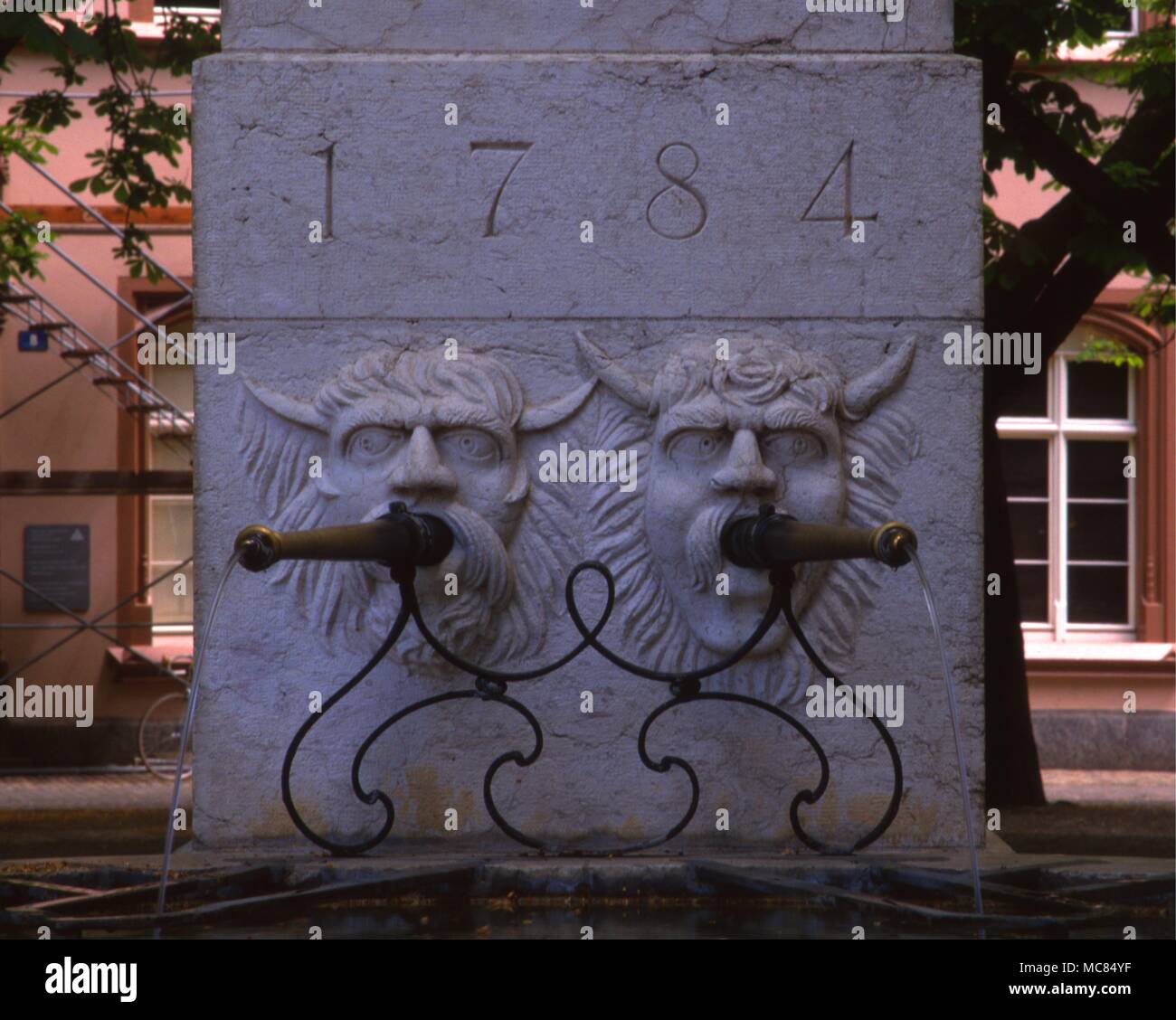Demonic heads as water-spouts on a fountain in Basle, Switzerland, with the date 1784 inscribed above. Stock Photo