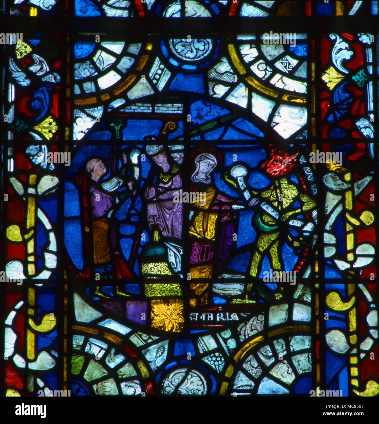 Incident from the story of how Theophilus entered into a pact with the Devil. In the end, the Virgin Mary snatched the pact [here in the form of a banderole] from the hands of the demon. Stained glass from Lincoln Cathedral. Stock Photo