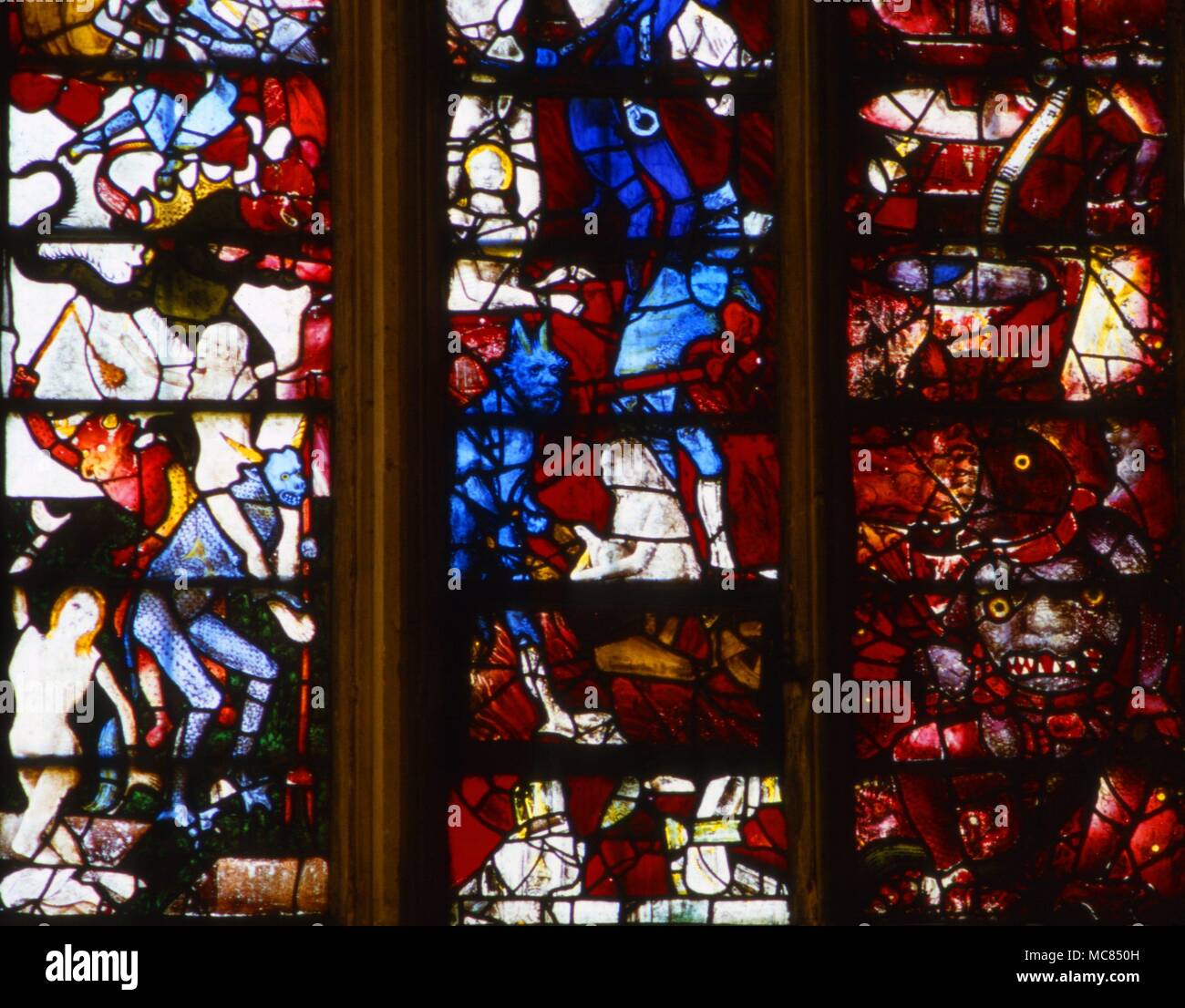 Demons torturing departed souls in Hell. Stained glass windows in Fairford Church, Gloucestershire. Stock Photo