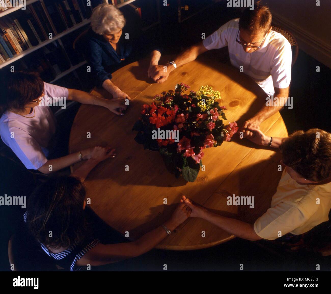 A seance group, joining hands in order to increase psychic powers. Stock Photo