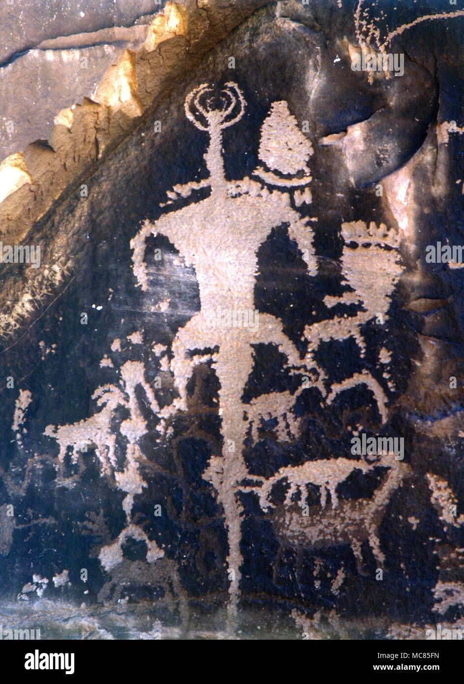 Petroglyphs - North American Indians. Incised and painted designs (petroglyphs) depicting (mainly) a horned medicine-man with a long tail. Such images have been claimed, by some, to depict aliens from space. These petroglyphs are on the so-called Newspaper Rock, in the Utah desert. Stock Photo