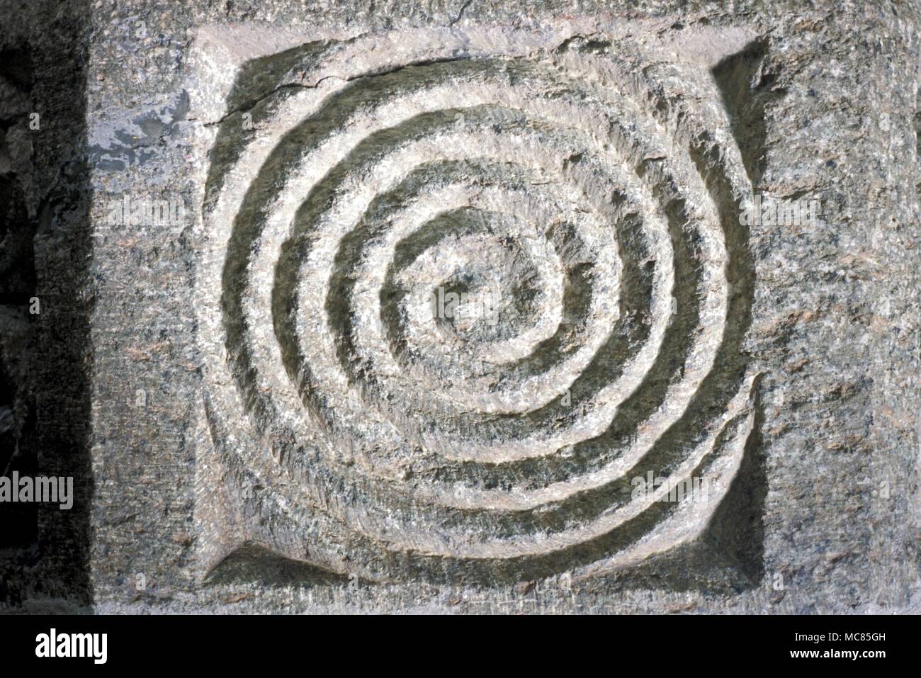 Spirals - Maze- Christian. A dance-pattern (sometimes called a maze), in the form of a spiral that leads from the periphery to the centre. Carving on the Norman font in the parish church of Lewannick, Cornwall. Stock Photo