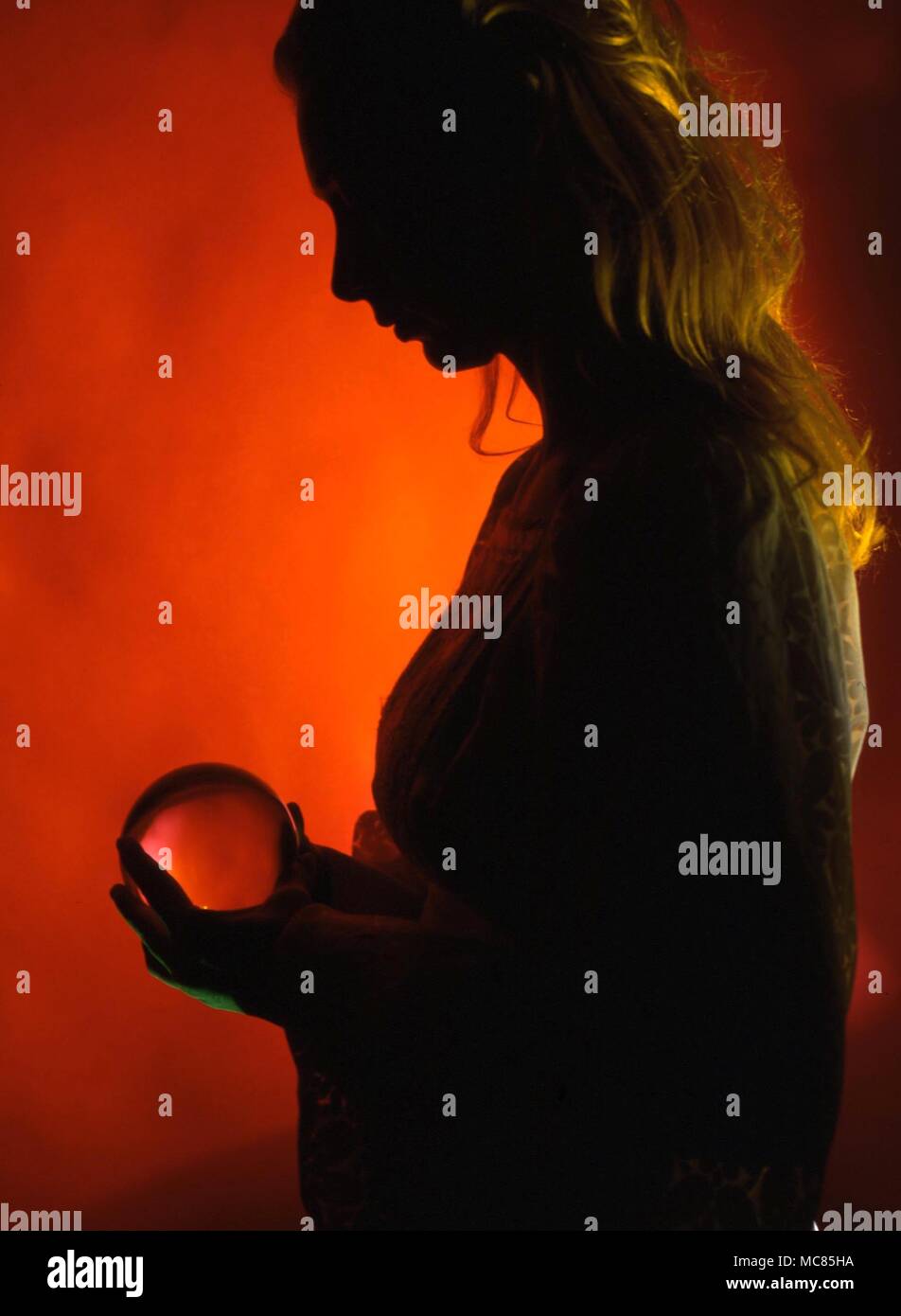 Divination. Girl in silhouette with crystal ball, used for divination. Stock Photo