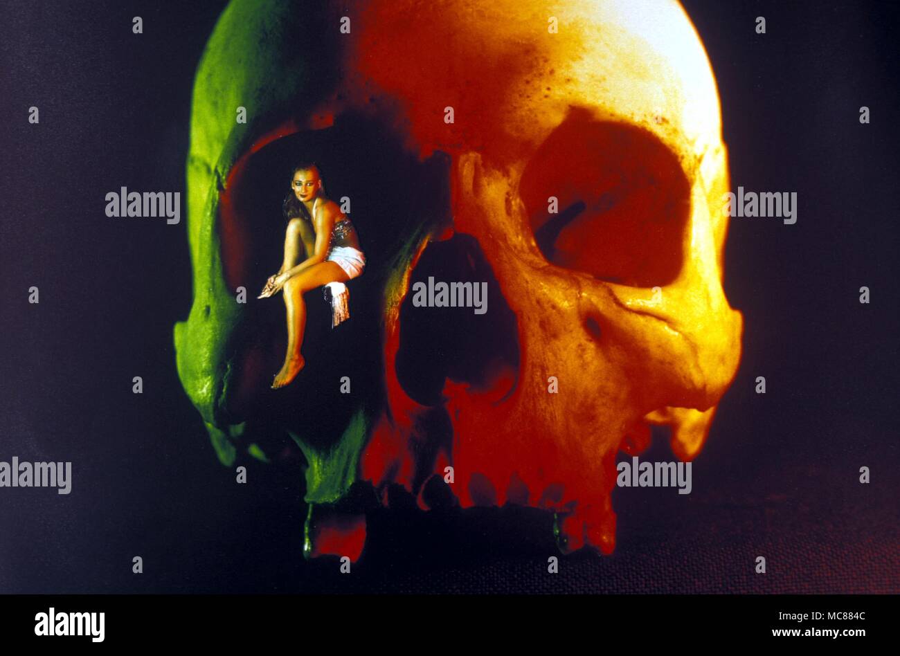 Fantasy. Girl sitting in the eye socket of a human skull. Stock Photo