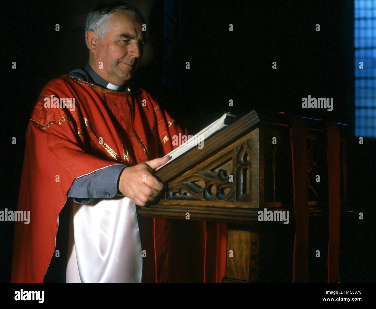 CHRISTIAN Anglican priest reading from the Holy Bible at a lectern Stock Photo