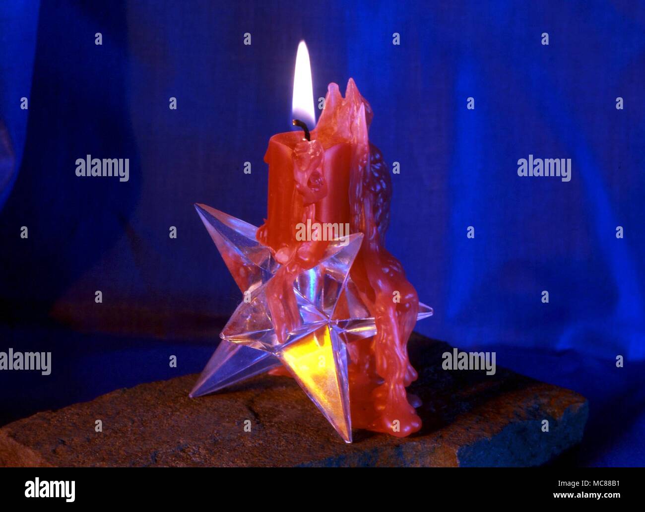 Burning red candle on magical polygonal methylmethacrylate base Stock Photo