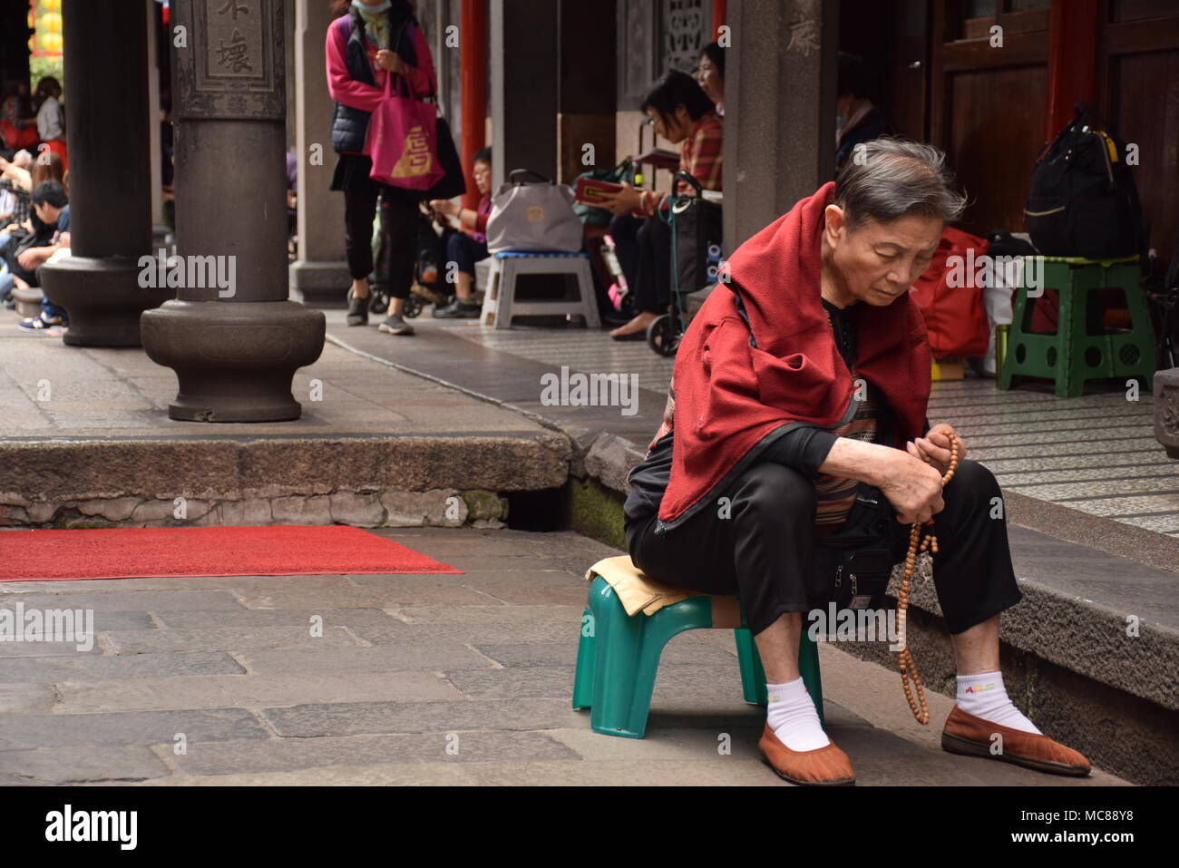 Old asian woman praying inside Longshan buddhist temple in Taipei, Taiwan Stock Photo