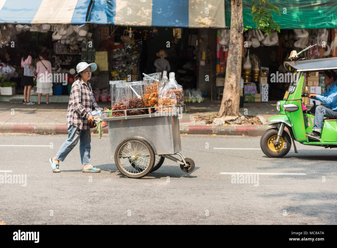 A street food vendor pushes her cart on a road in Bangkok Thailand Stock Photo