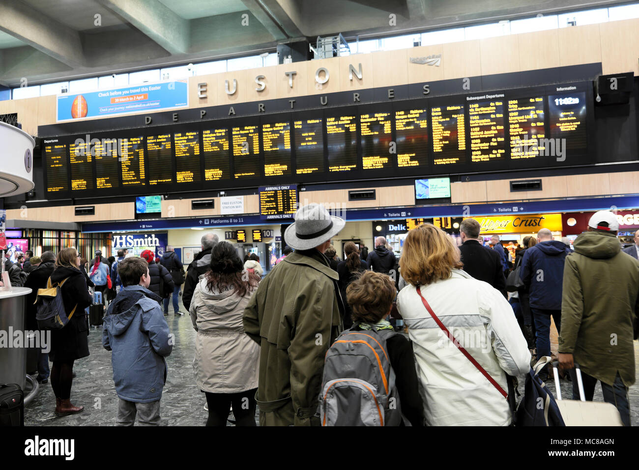 Passengers standing on the concourse check the departure board for their train leaving time at Euston Station in London UK  KATHY DEWITT Stock Photo