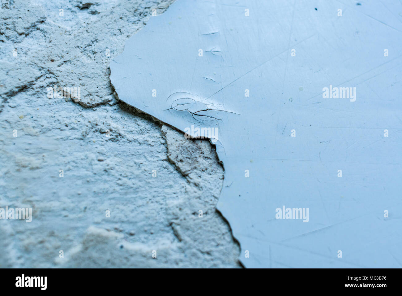 Grey surface with pieces of peel-off paint and putty. Selective focus and copy space. Stock Photo
