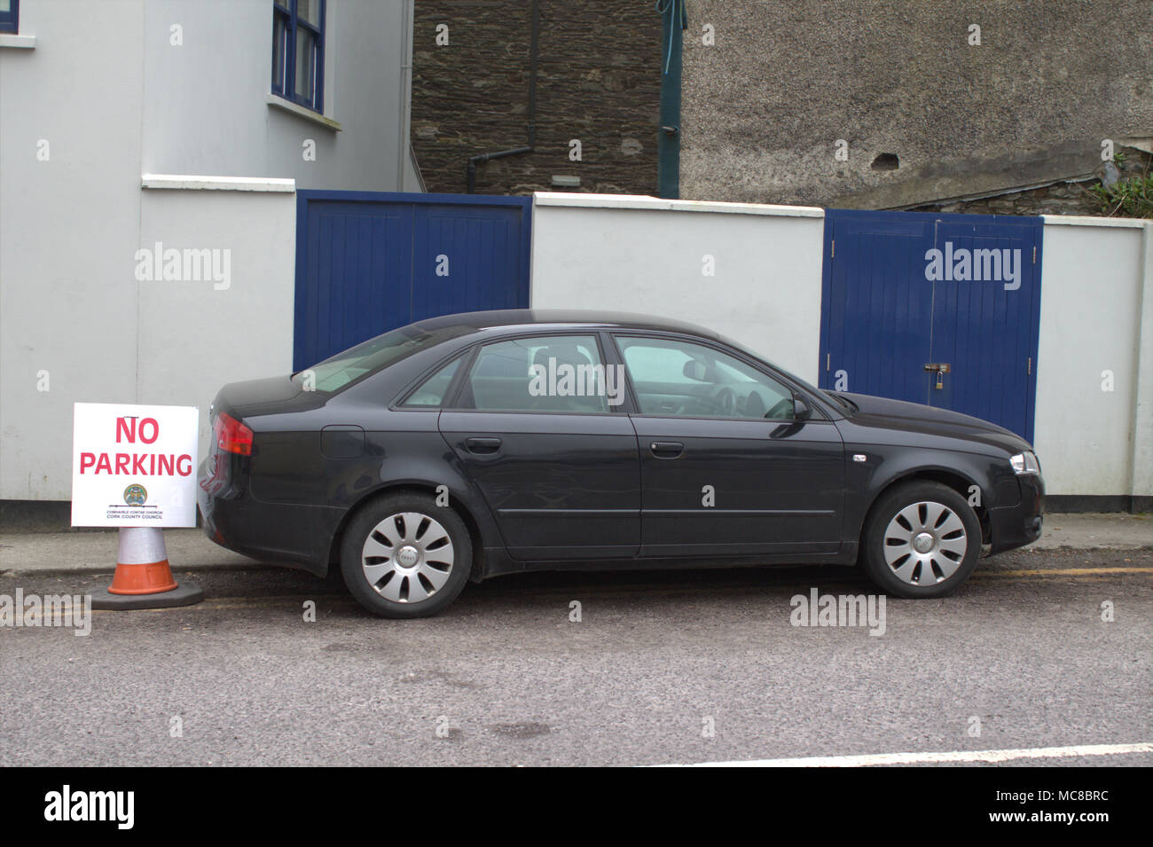 car ignoring a no parking sign and blocking a gateway, restricting access to the property or building, and blocking the footpath, sidewalk. Stock Photo