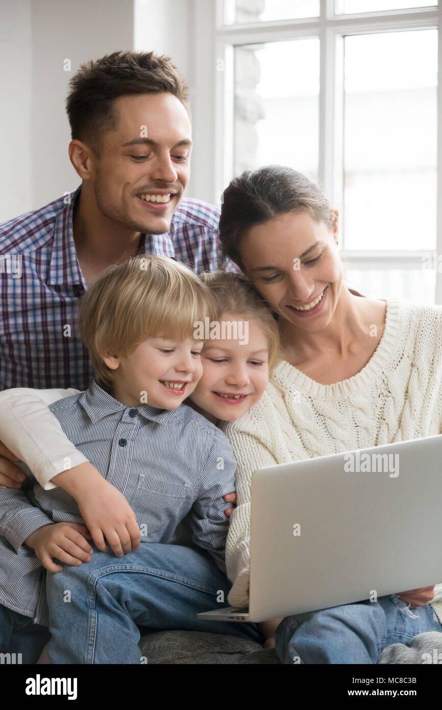 Happy family with adopted kids having fun using laptop together sitting ...