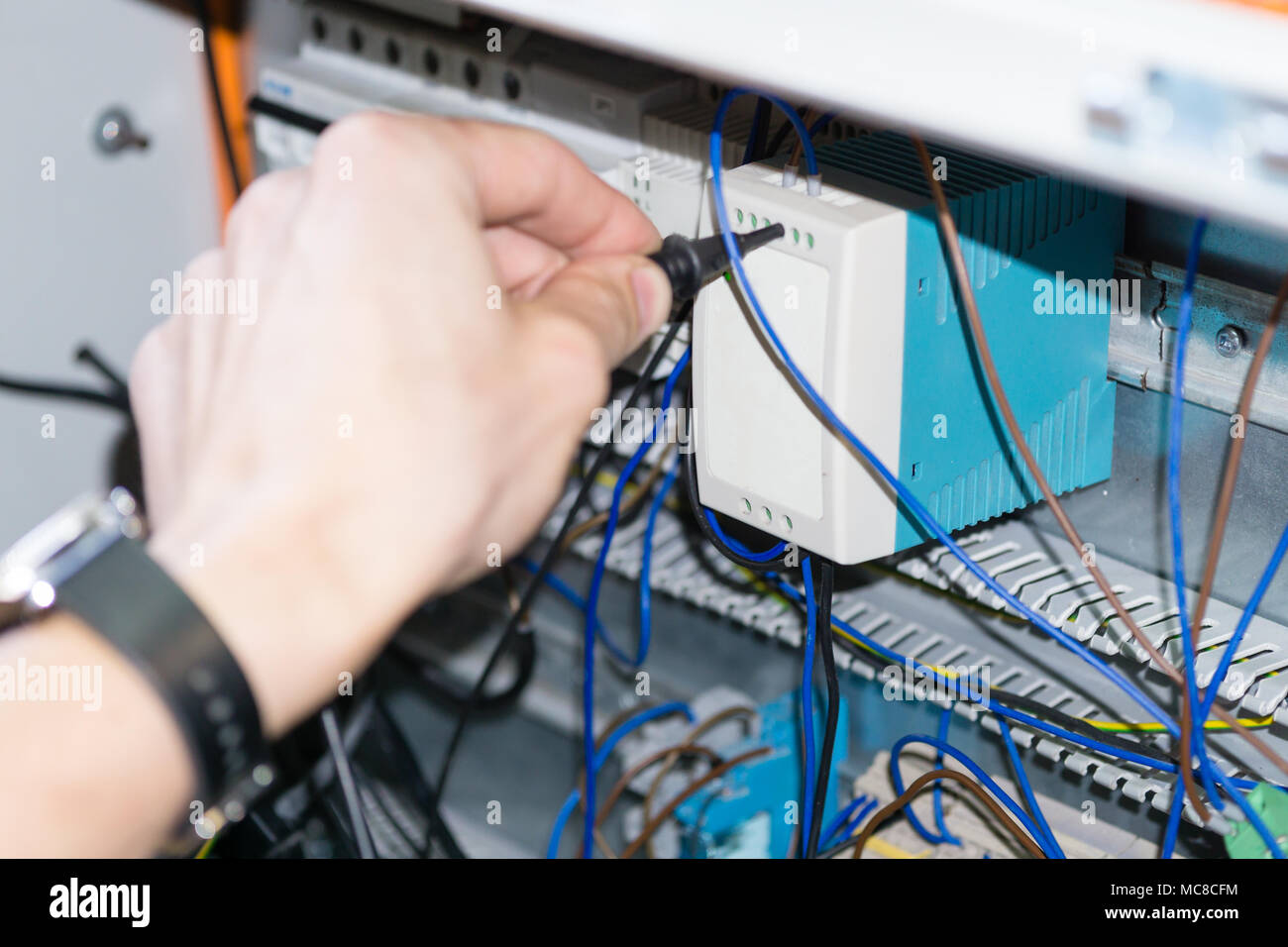 engineer hands installing electrical components in fuse box. Industry 4. Measuring voltage Stock Photo