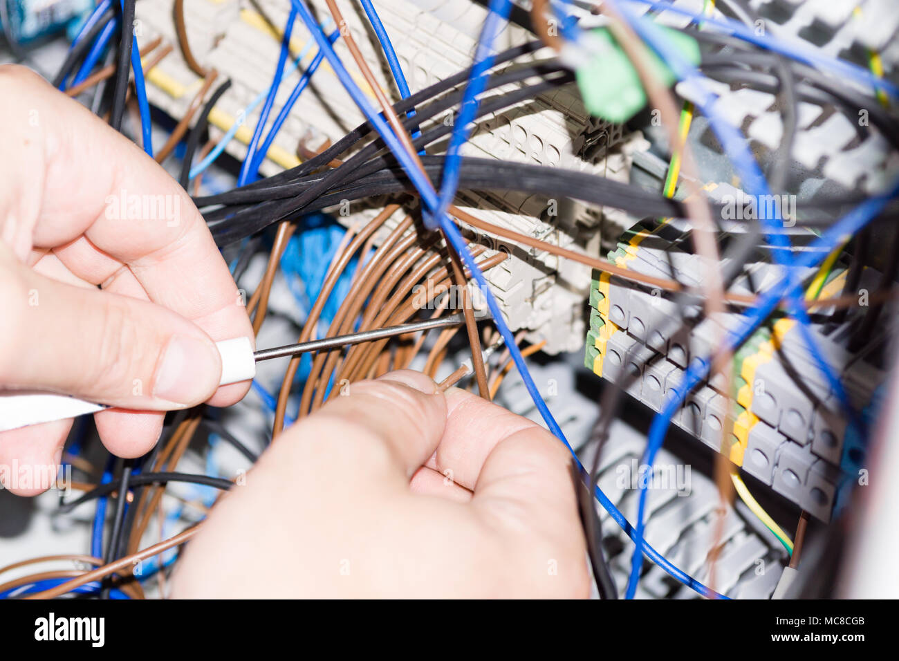 engineer hands installing electrical components in fuse box. Industry 4. Measuring voltage Stock Photo