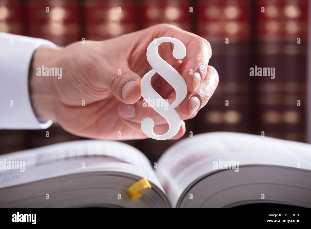 Close-up Of A Judge's Hand Holding White Paragraph Symbol Stock Photo