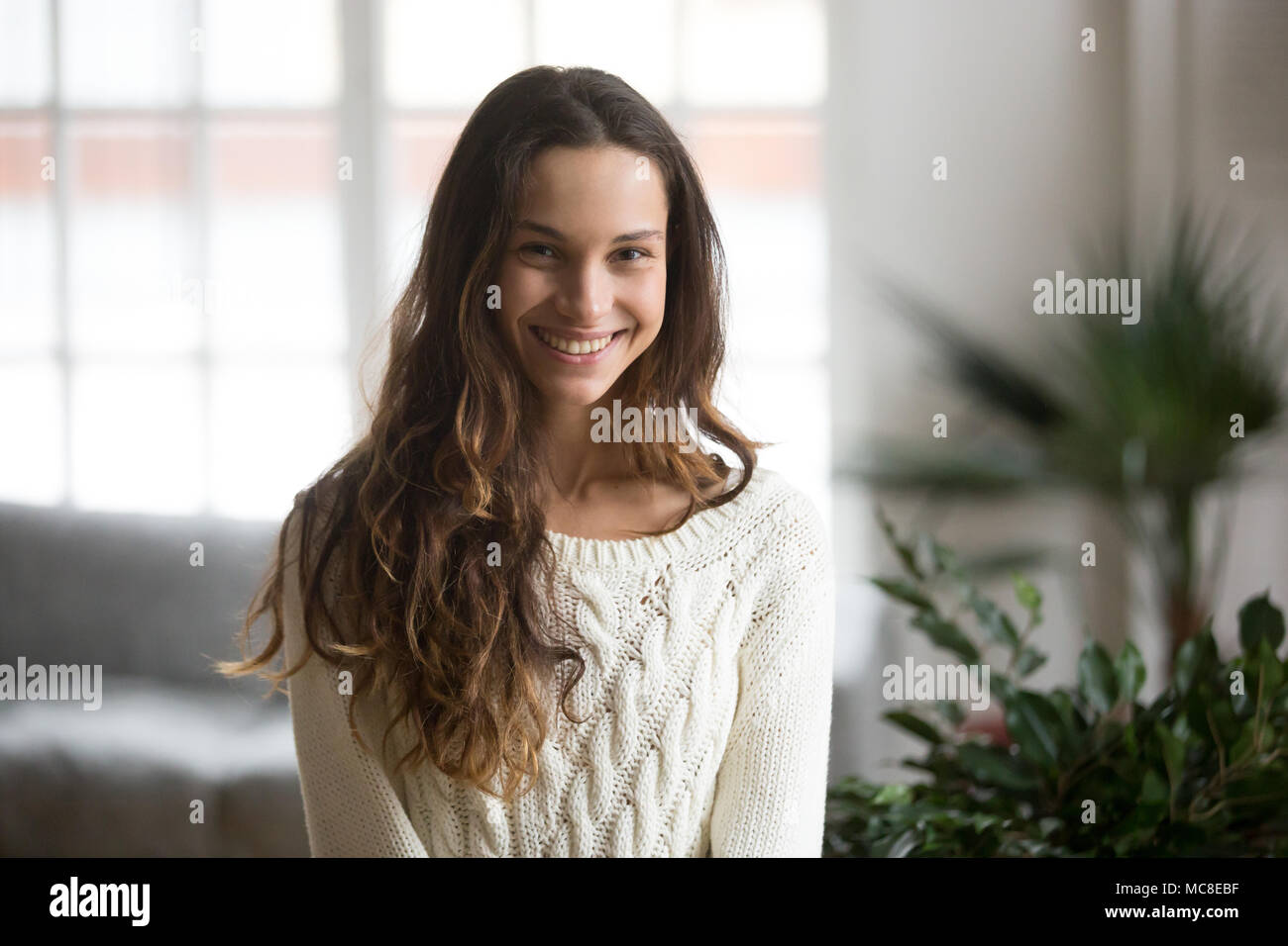 Happy friendly mestizo woman posing indoor at home in casual clothes, teenage student or young girl with beautiful face and wide smile looking at came Stock Photo