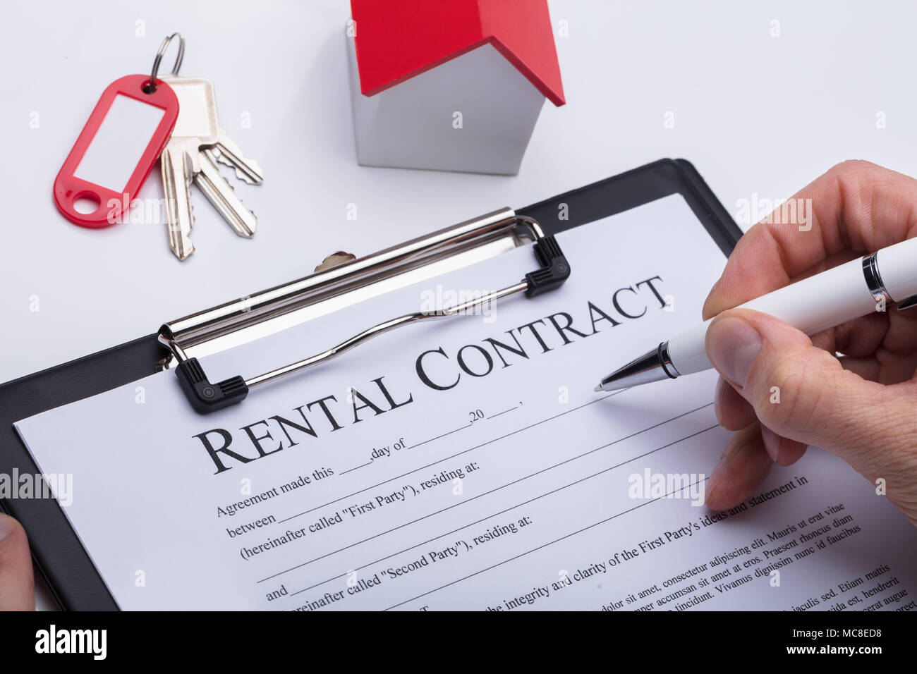 Human Hand Filling Rental Contract Form With House Model And Key On