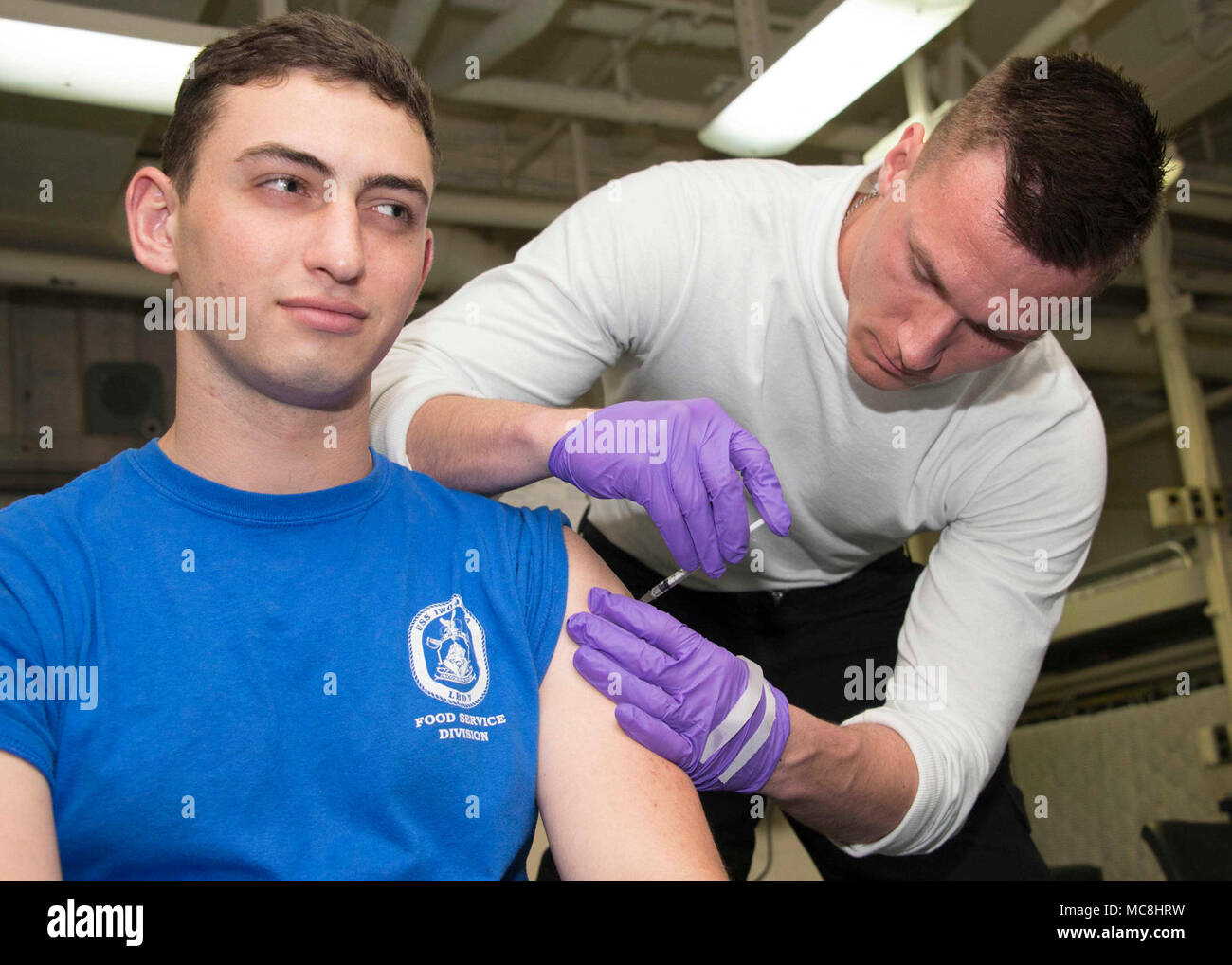 5TH FLEET AREA OF OPERATIONS (March 28, 2018) Air Traffic Controlman Antony Pilipenko receives an Anthrax immunization administered by Corpsman 3rd Class Coltin Russell aboard the Wasp-class amphibious assault ship USS Iwo Jima (LHD 7), March 28, 2018. Iwo Jima, homeported in Mayport, Florida, is on a regularly scheduled deployment to the U.S. 5th Fleet area of operations in support of maritime security operations to reassure allies and partners, and preserve the freedom of navigation and the free flow of commerce in the region. Stock Photo