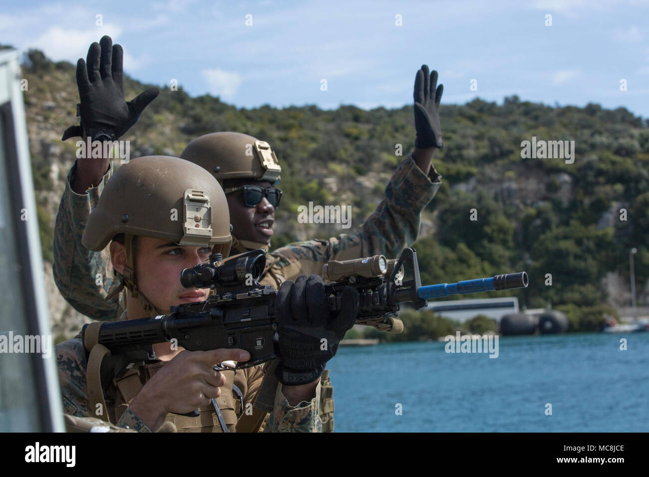 U.S. Marines assigned to Maritime Raid Force (MRF), 26th Marine Expeditionary Unit (MEU), warn role players to show their hands during small boat investigation training with NATO Maritime Interdiction Operations Centre (NMIOTC) instructors at Naval Base Souda Bay, Crete, Greece, Mar. 13, 2018. NMIOTC hosted the MRF’s training as part of a two-week course designed to teach maritime interdiction techniques to NATO partner nations. Stock Photo