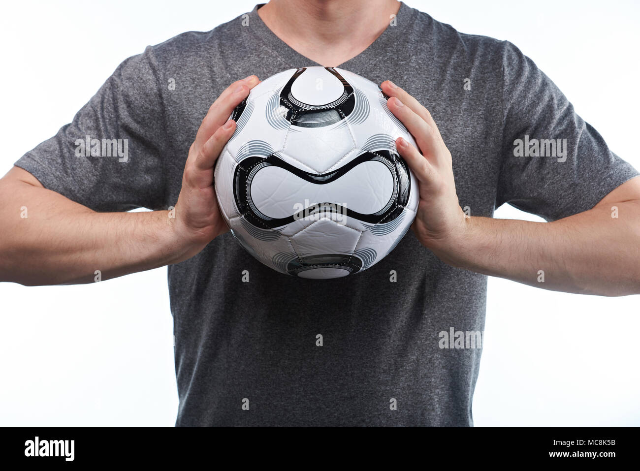Man catch football ball with both hands on gray uniform background Stock Photo