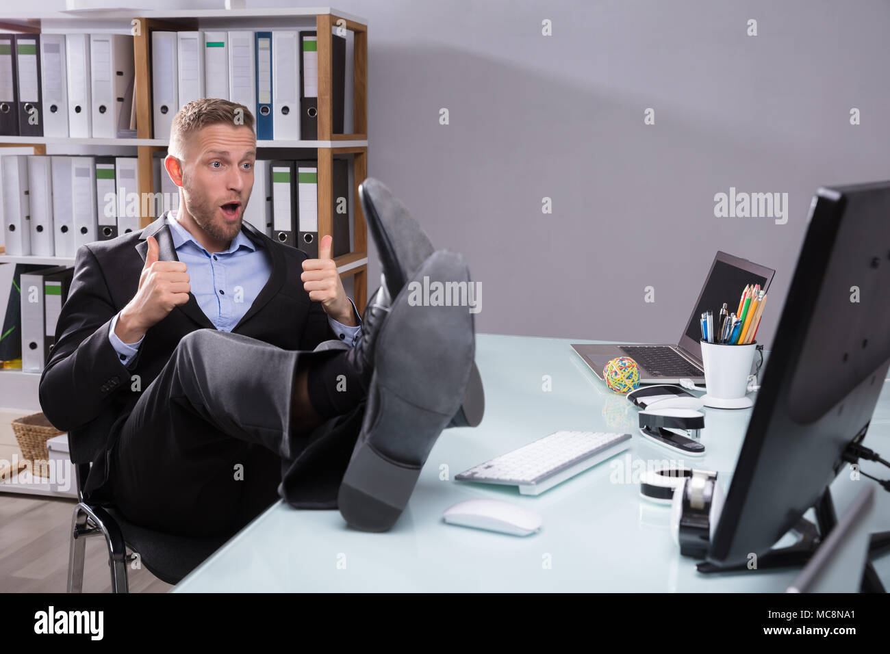 Young Businessman Looking At Computer Gesturing Thumbs Up Stock Photo