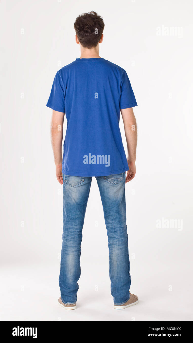 Boy in blue T-shirt and jeans standing back to cameraman Stock Photo