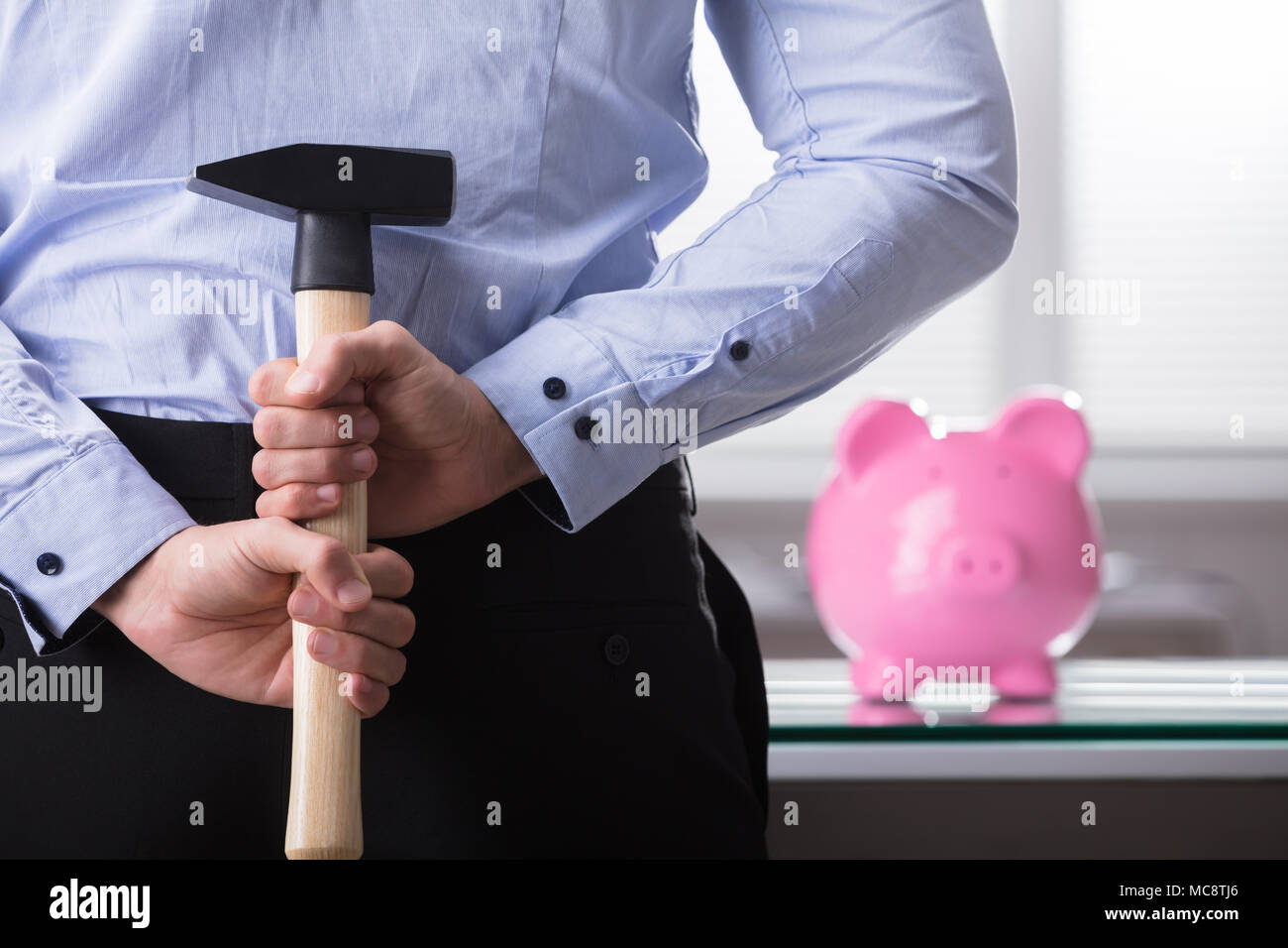 Businessperson Hiding Hammer In Front Of Piggy Bank Stock Photo - Alamy
