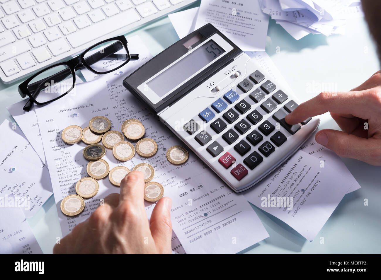 Businessperson's Hand Calculating Receipt With Coins And Eyeglasses On ...