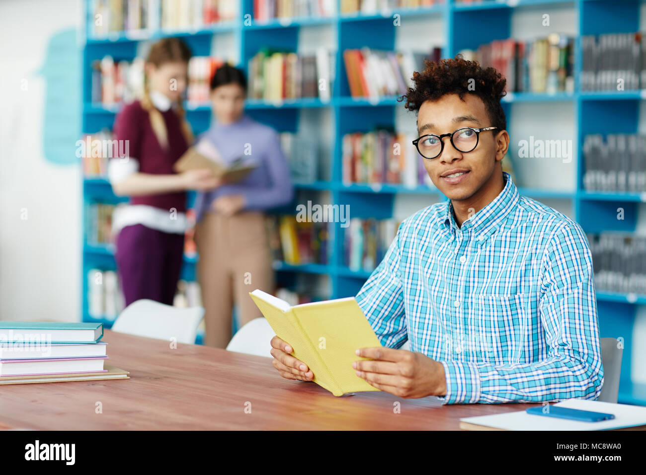 Young guy with open book reading passages that were given as home task for next lesson Stock Photo