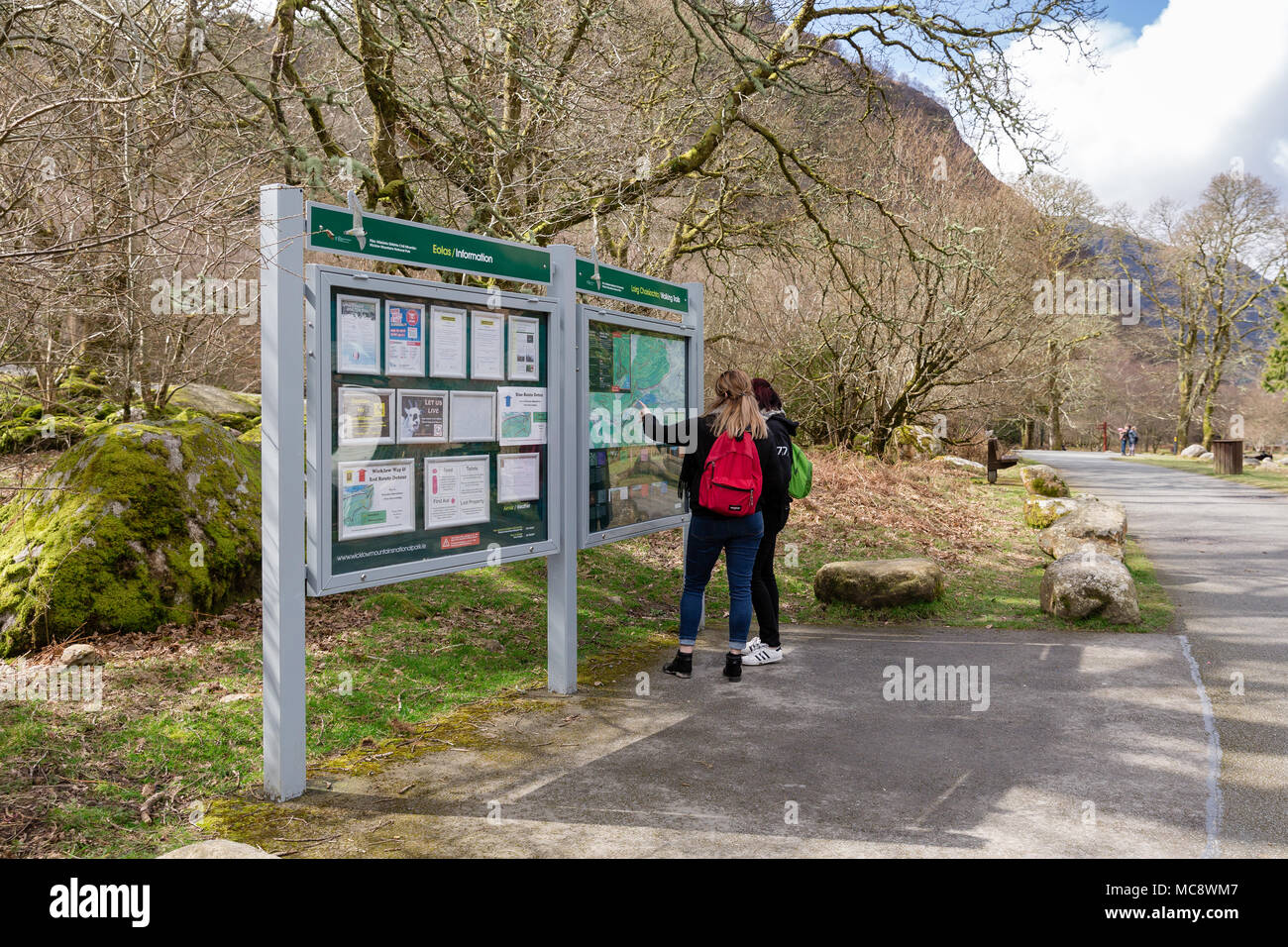 Two girls with backpacks looking at the Information board with map of walking trials in Glendalough at the Wicklow Mountains National Park in Ireland Stock Photo