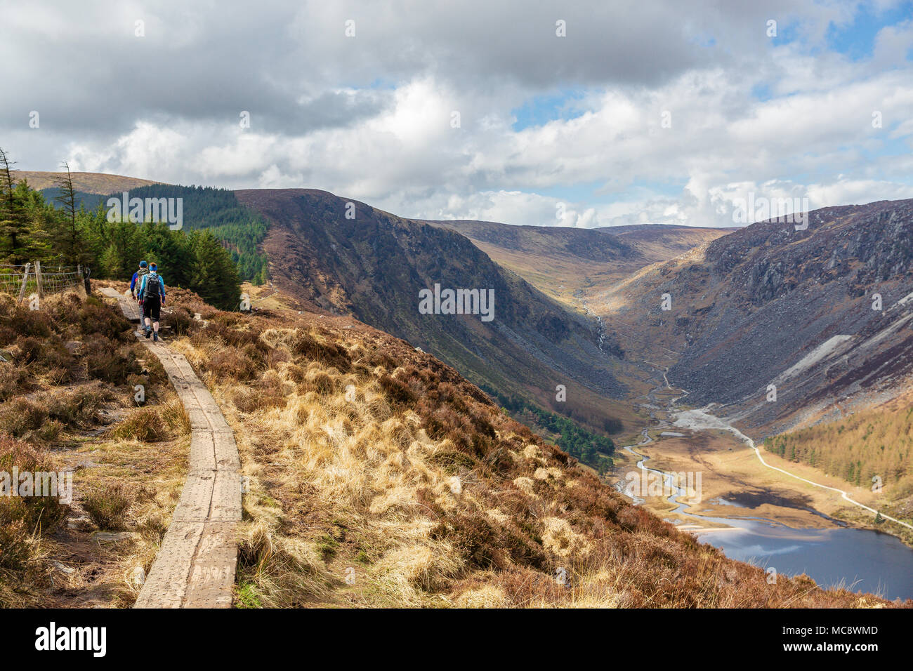 Hikers on walking trial climbing the Spinc ridge over the spectacular Glendalough and Glenealo Valleys in Wicklow Mountains National Park Stock Photo