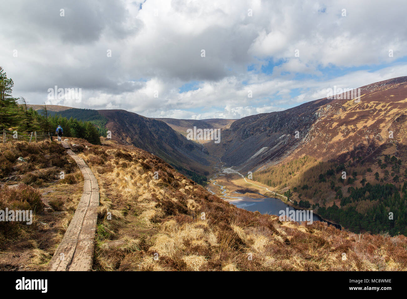 Hikers on walking trial climbing the Spinc ridge over the spectacular Glendalough and Glenealo Valleys in Wicklow Mountains National Park Stock Photo