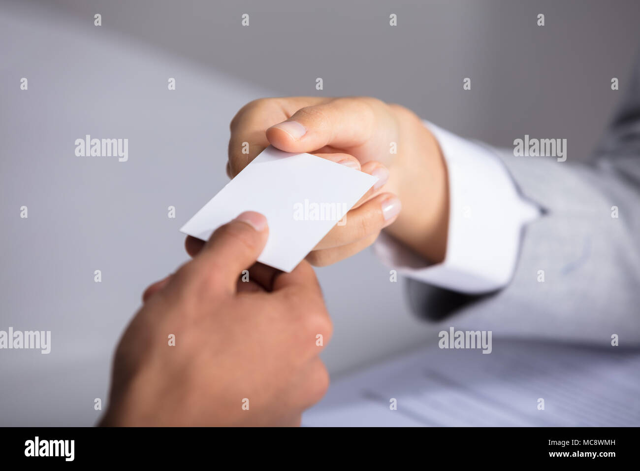 Close-up Of Businessperson's Hand Giving Blank White Card To Partner Stock Photo