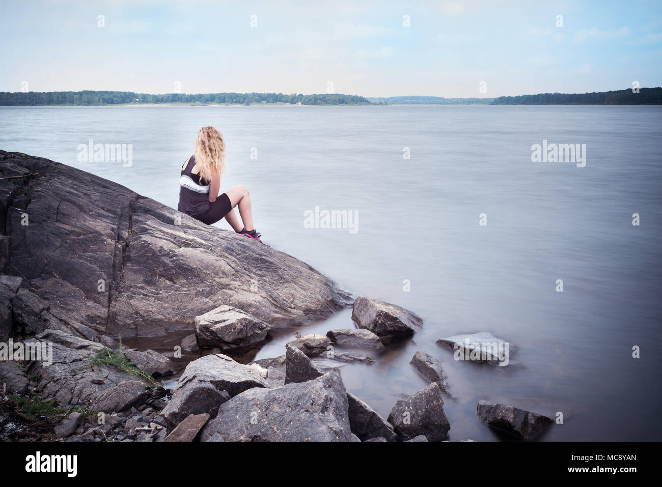 Young woman sitting on a rock hi-res stock photography and images - Alamy