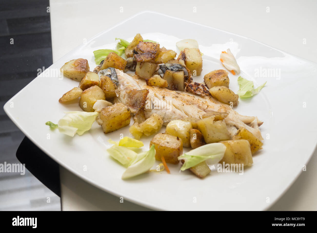 sea bass in the dish with potatoes and salad Stock Photo