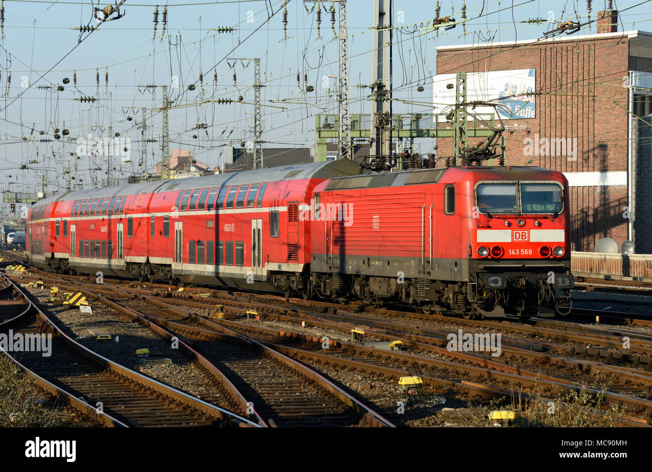 A service departs from Cologne station in Germany toward the north, with a DB class 143 locomotive Stock Photo