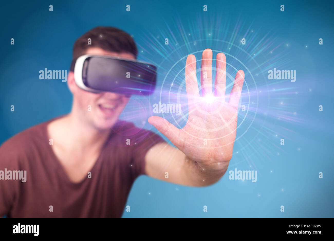 Young impressed man wearing virtual reality goggles with blue circles ...