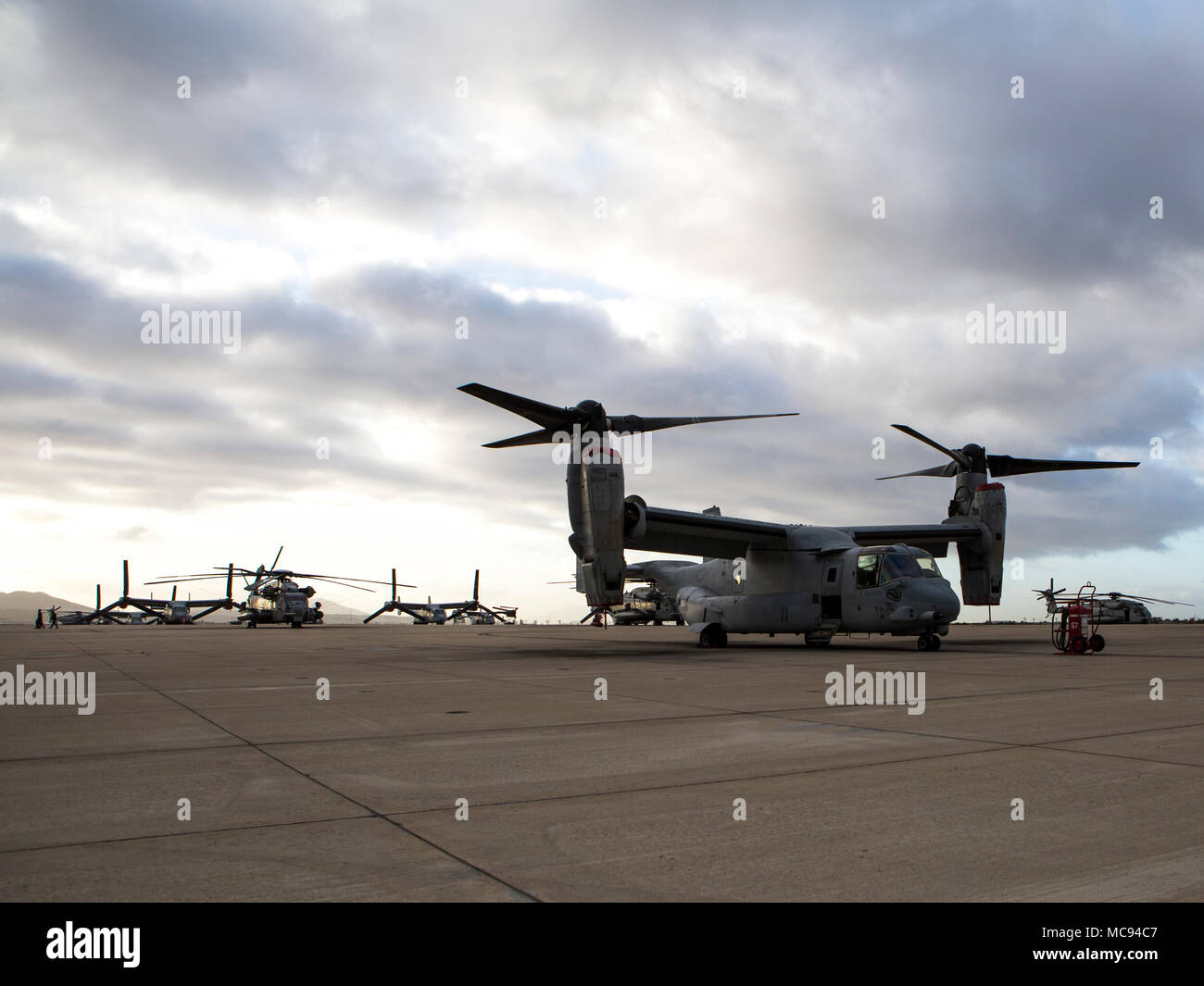 An MV-22B Osprey assigned to Marine Medium Tiltrotor Squadron (VMM) 166 (Reinforced), Marine Aircraft Group 16, 3rd Marine Aircraft Wing, rests on the flight line during sunrise at Marine Corps Air Station Miramar, Calif., April 12. Marine Heavy Helicopter Squadron (HMH) 361, Marine Light Attack Helicopter Squadron (HMLA) 469 and VMM-166 consolidated to become VMM-166 (Rein) for an upcoming combat deployment with the 13th Marine Expeditionary Unit. MCAS Miramar is home to 3rd MAW and 19 of its squadrons. (U.S. Marine Corps photo by Cpl. Becky Calhoun/Released) Stock Photo