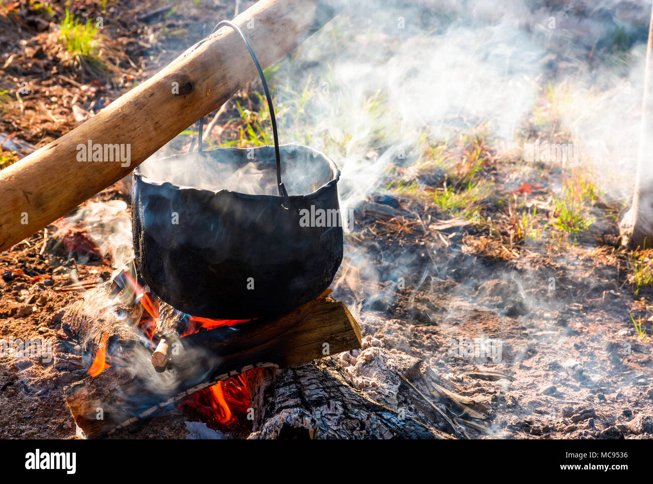 cauldron in steam and smoke on open fire. outdoor cooking concept. old  fashioned way to make food Stock Photo - Alamy