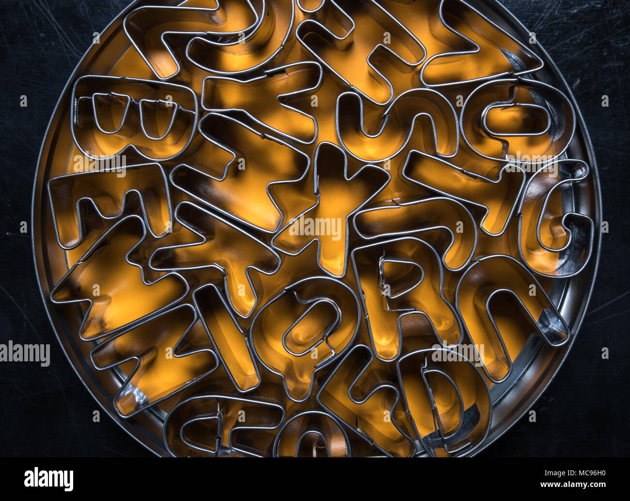 Tin of Alphabet Cookie Cutters with orange background Stock Photo